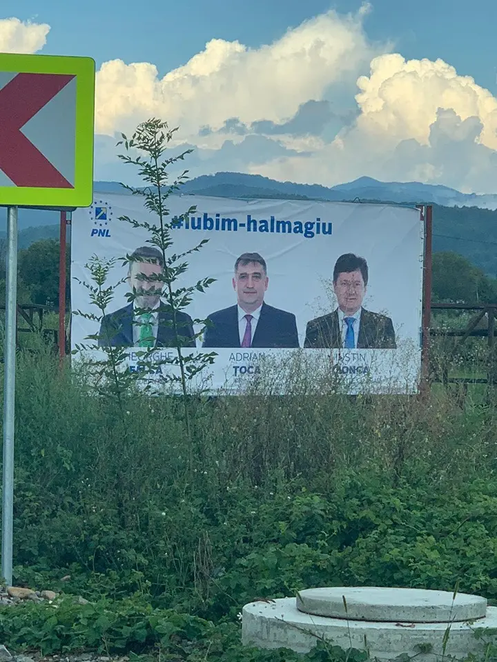 De ciudă că nu i-au dat bani anul ăsta nici măcar de COVID, primarul Adrian ȚOCA și-a pus bannerul cu CIONCA și FALCĂ printre BĂLĂRII, deasupra unui capac de canal, decizând să se susțină singur!